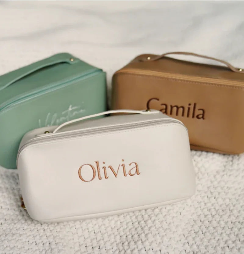 Four personalized cosmetic bags in different colors with names engraved on them.