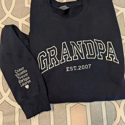 Black sweatshirt with 'GRANDPA EST.2007' text on a patterned surface