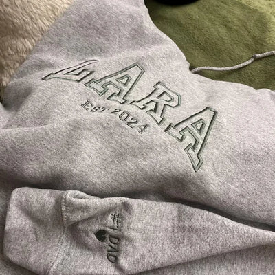 Gray hoodie with 'LARA' logo and text on a green surface