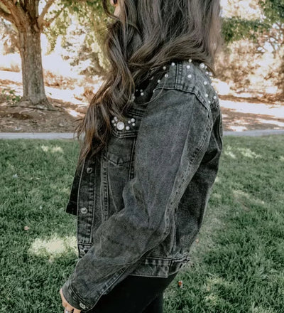 Person wearing a studded denim jacket outdoors